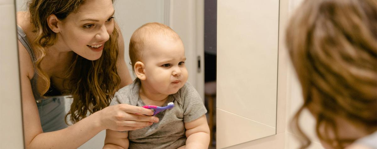 Young woman showing a baby a toothbrush